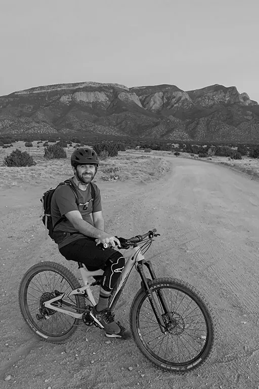 A mountain biker resting on a bike in front of a mountain